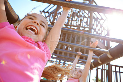 Buy stock photo Shot of two little girls hanging on the monkey bars at the playground