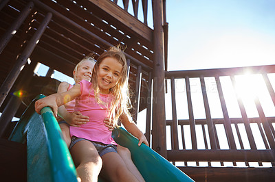 Buy stock photo Shot of two little girls on a slide at the play park