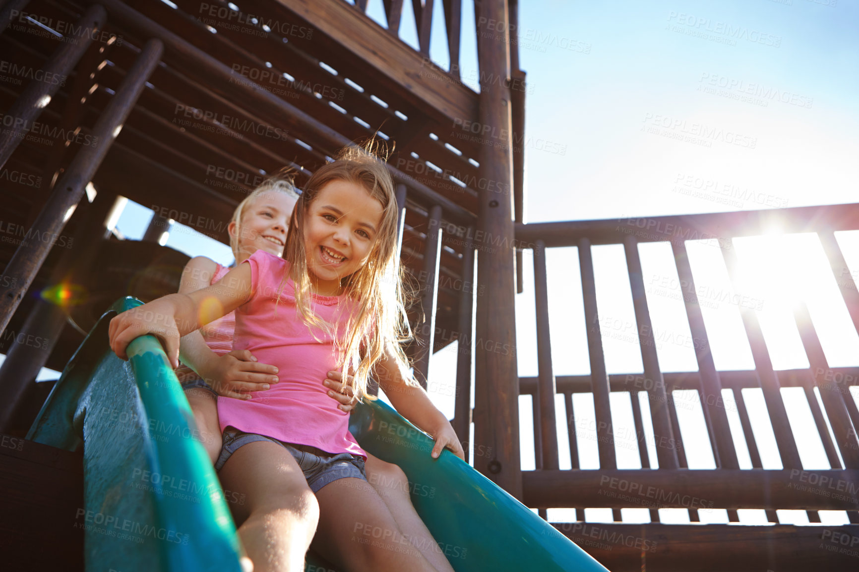 Buy stock photo Shot of two little girls on a slide at the play park