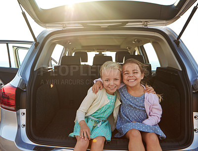 Buy stock photo Shot of two little girls sitting in the trunk of a car