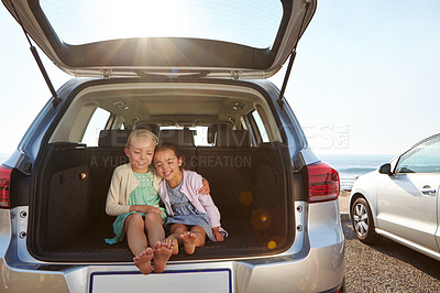 Buy stock photo Shot of two little girls sitting in the trunk of a car