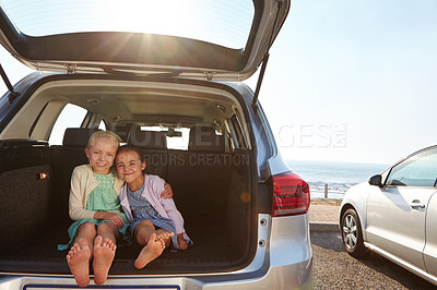 Buy stock photo Shot of two little girls sitting in the trunk of a car