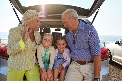 Buy stock photo Shot of two little girls sitting in the trunk of a car with their grandparents