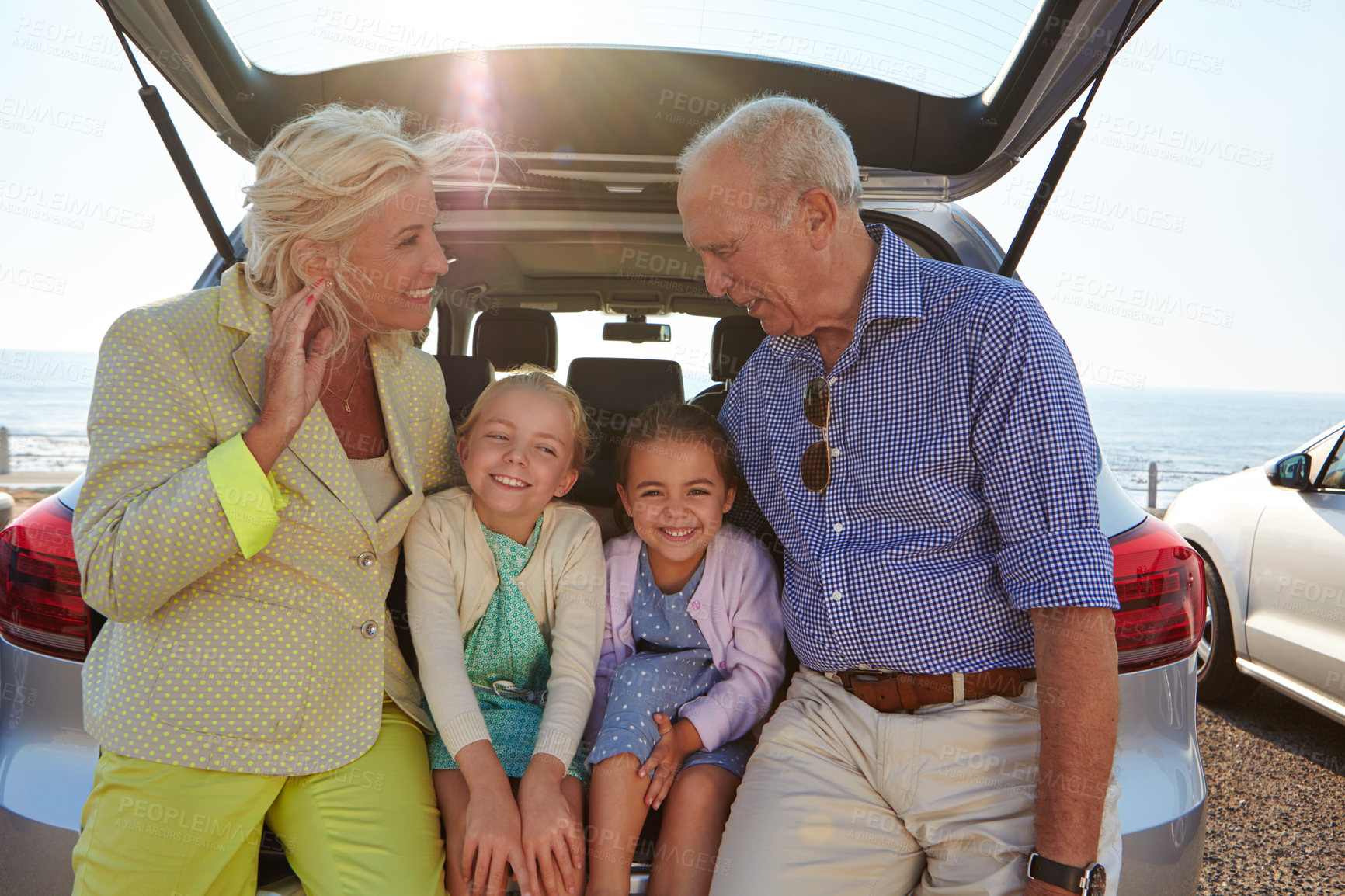 Buy stock photo Shot of two little girls sitting in the trunk of a car with their grandparents