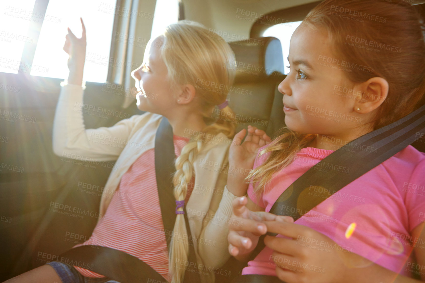 Buy stock photo Road trip, girls and siblings in backseat with car games, summer vacation and family journey for smile. Pointing, flare and children in vehicle together, show landmark and travel activity for bonding