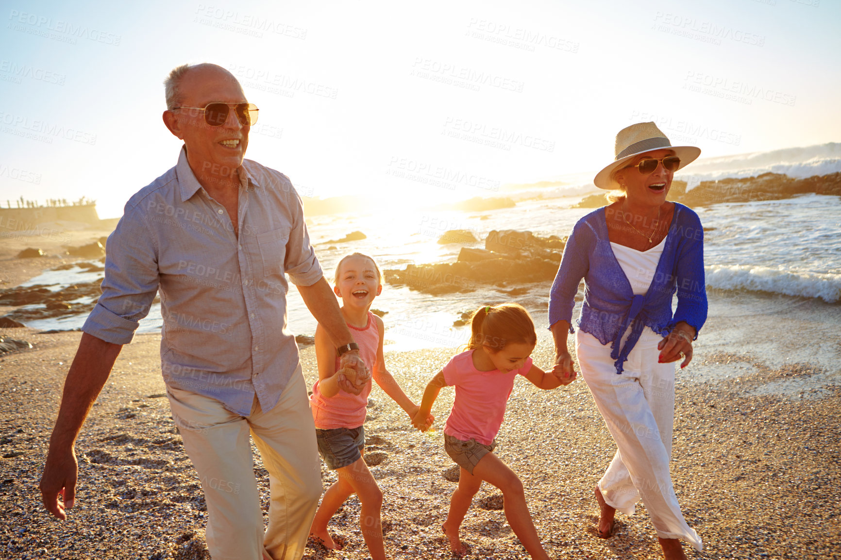 Buy stock photo Shot of a grandparents enjoying a day at the beach with their granddaughters