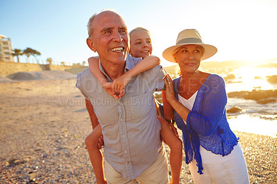 Buy stock photo Shot of a grandparents enjoying a day at the beach with their granddaughter