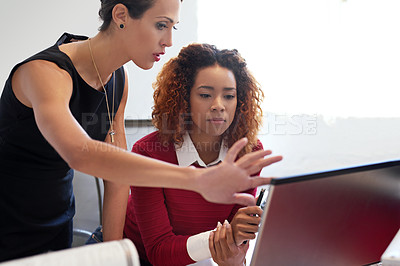 Buy stock photo Shot of two businesswoman working together at a computer in an office