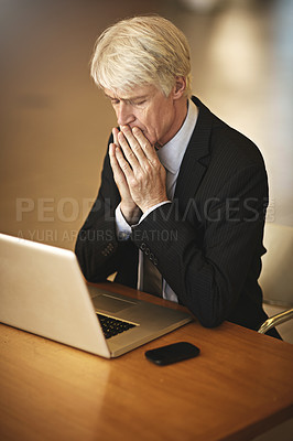 Buy stock photo Cropped shot of a senior businessman looking worried while working on his laptop
