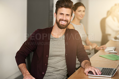 Buy stock photo Portrait of a young designer sitting in an office with his colleague blurred in the background