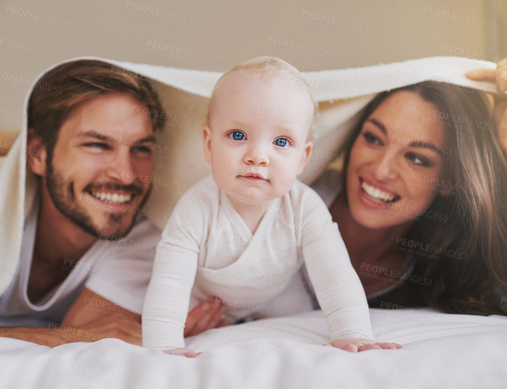 Buy stock photo Mother, father and baby under blanket on bed for love, care and quality time together. Portrait of playful child, happy family and kids relaxing in bedroom with bedding fort, fun and bonding in house