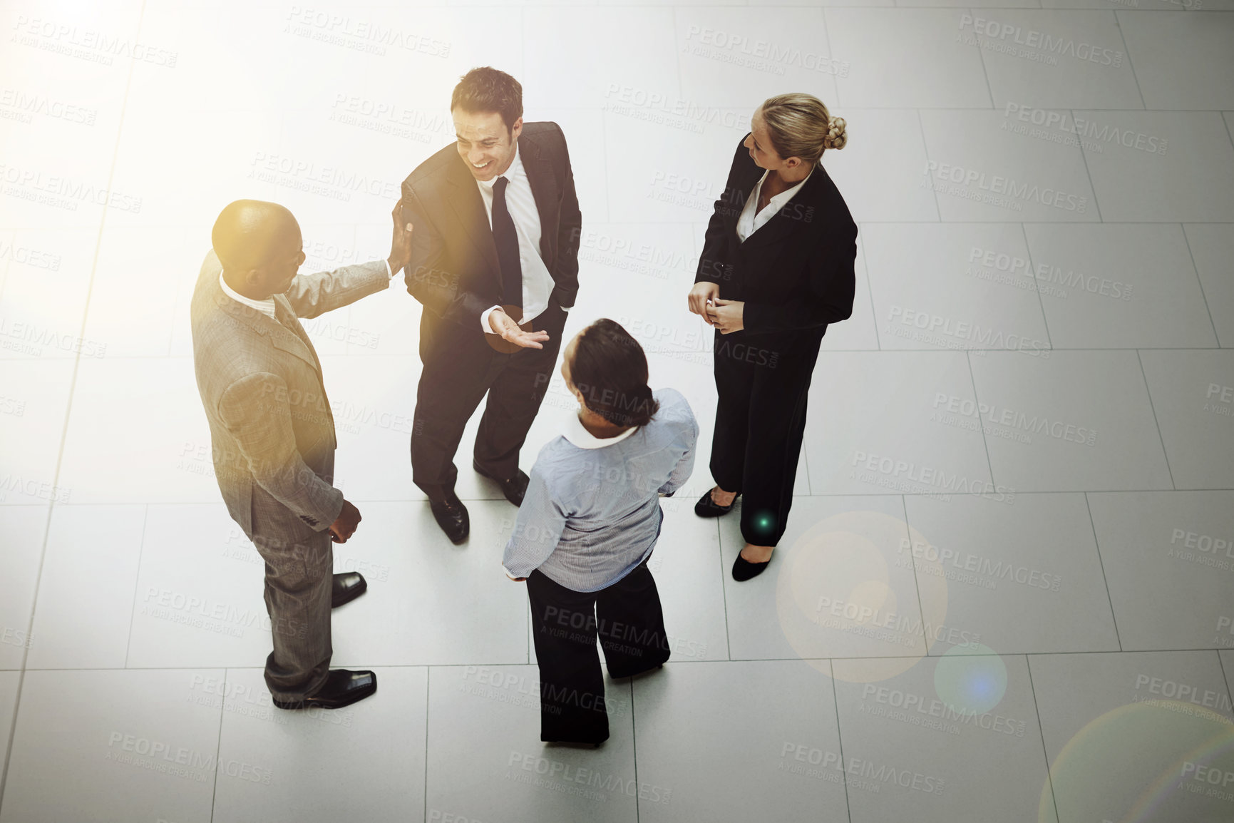 Buy stock photo High angle shot of a group of businesspeople talking in the office lobby