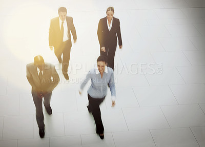 Buy stock photo High angle shot of a group of businesspeople walking through the office lobby