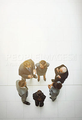 Buy stock photo High angle shot of a group of businesspeople talking in the office lobby