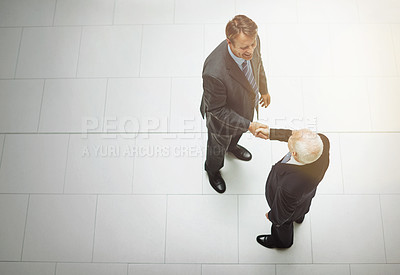 Buy stock photo High angle shot of two businessmen shaking hands in the office lobby