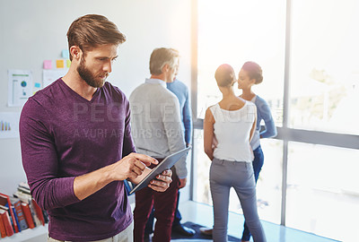 Buy stock photo Shot of a young businessman using a digital tablet in an office setting