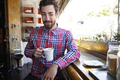 Buy stock photo Shot of a young man drinking a cup of coffee in a coffee shop