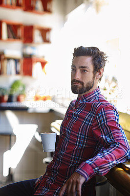 Buy stock photo Shot of a young man holding a cup of coffee in a cafe