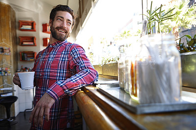 Buy stock photo Shot of a young man holding a cup of coffee in a cafe