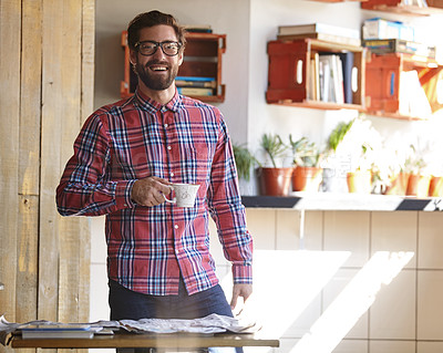 Buy stock photo Shot of a young man having coffee in a cafe with the newspaper lying on the table in front of him