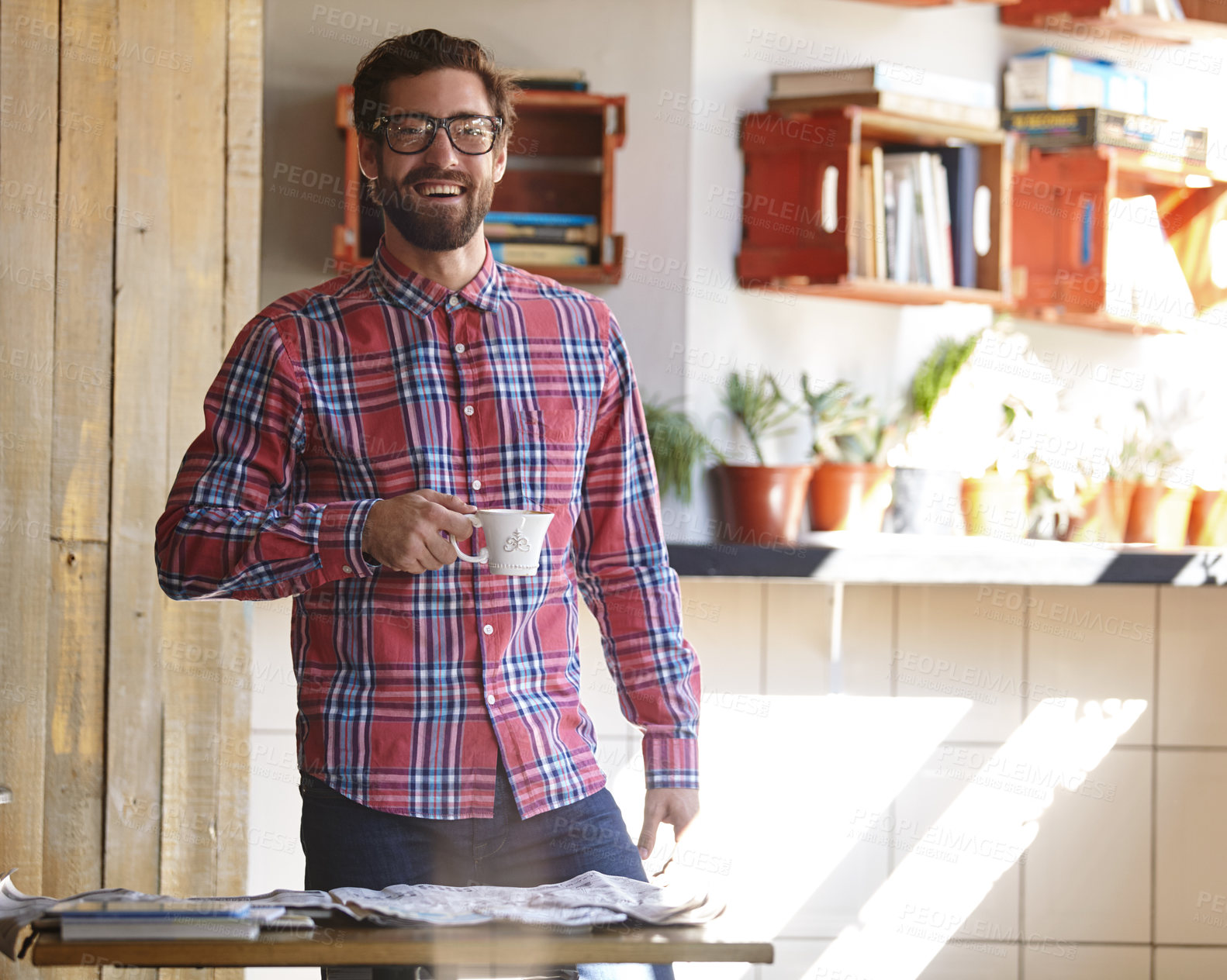 Buy stock photo Shot of a young man having coffee in a cafe with the newspaper lying on the table in front of him