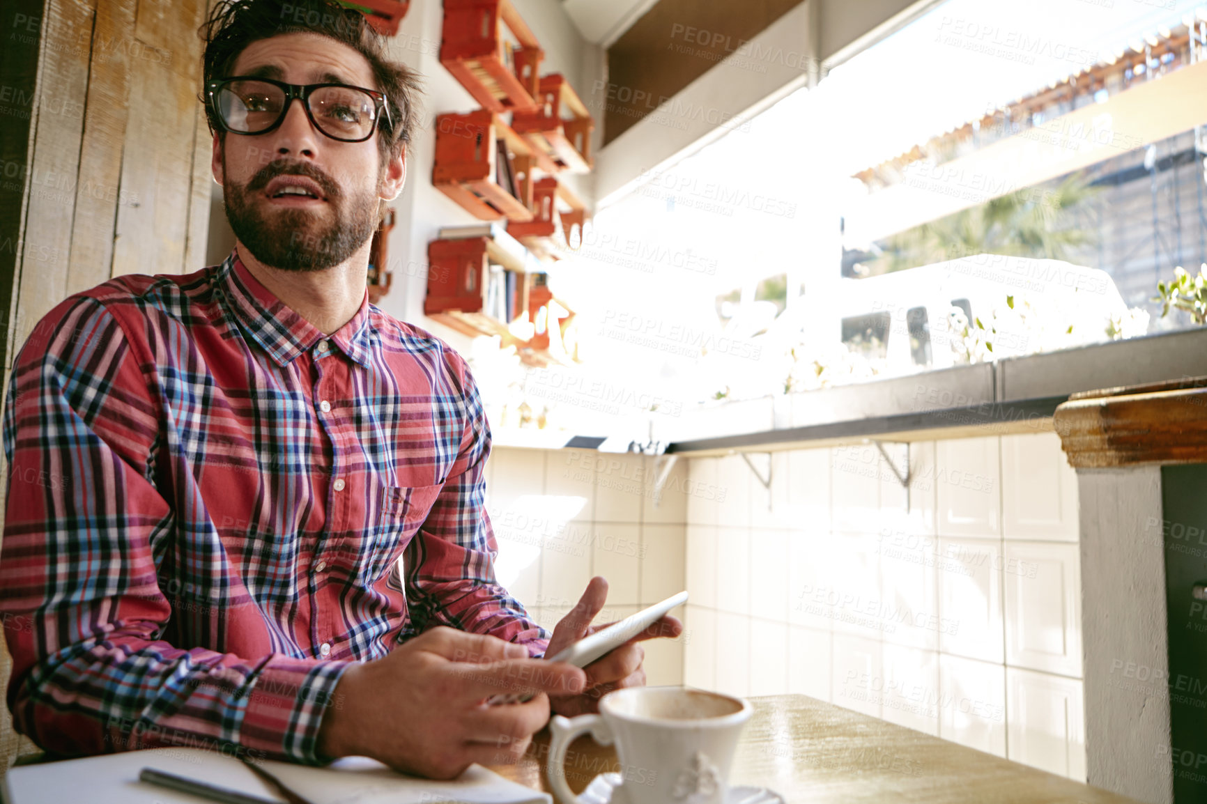 Buy stock photo Shot of a young man using his cellphone while sitting in a cafe