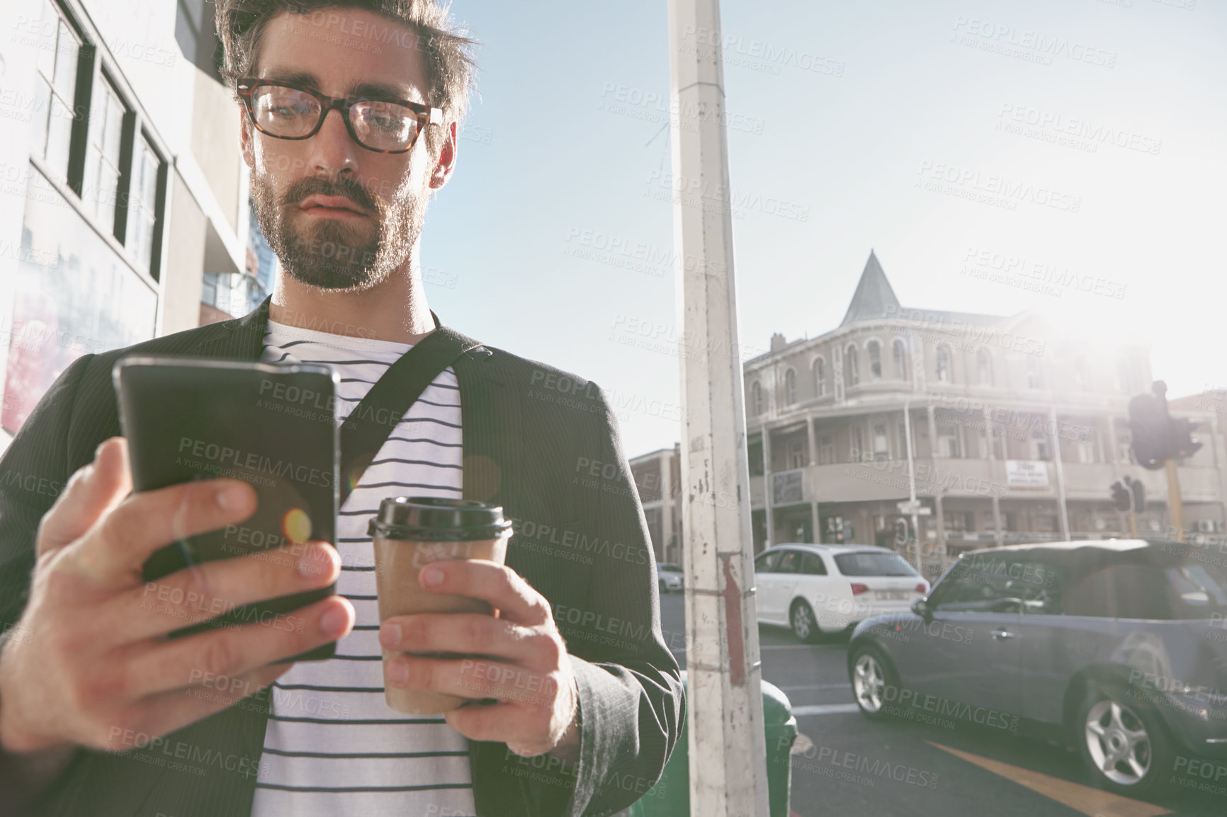 Buy stock photo Shot of a stylish young man using a cellphone while out in the city