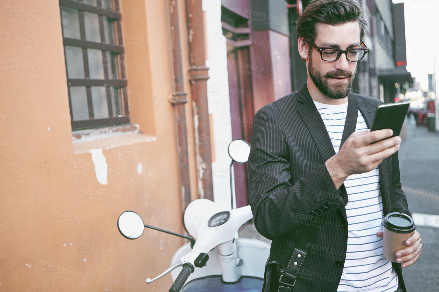 Buy stock photo Shot of a stylish young man using a cellphone while out in the city