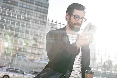Buy stock photo Shot of a stylish young man using a cellphone while out in the city