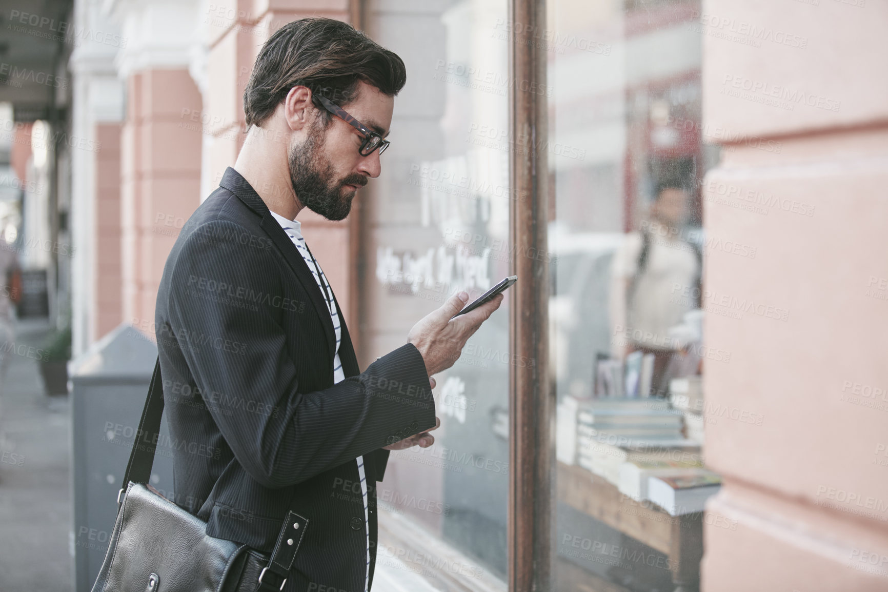 Buy stock photo Shot of a stylish young man using a cellphone while out in the city