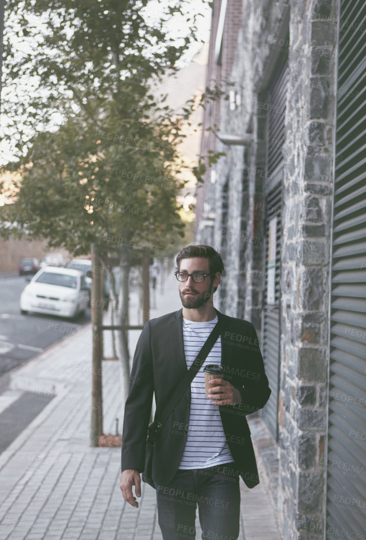 Buy stock photo Shot of a young man having a coffee on the go while out walking in the city