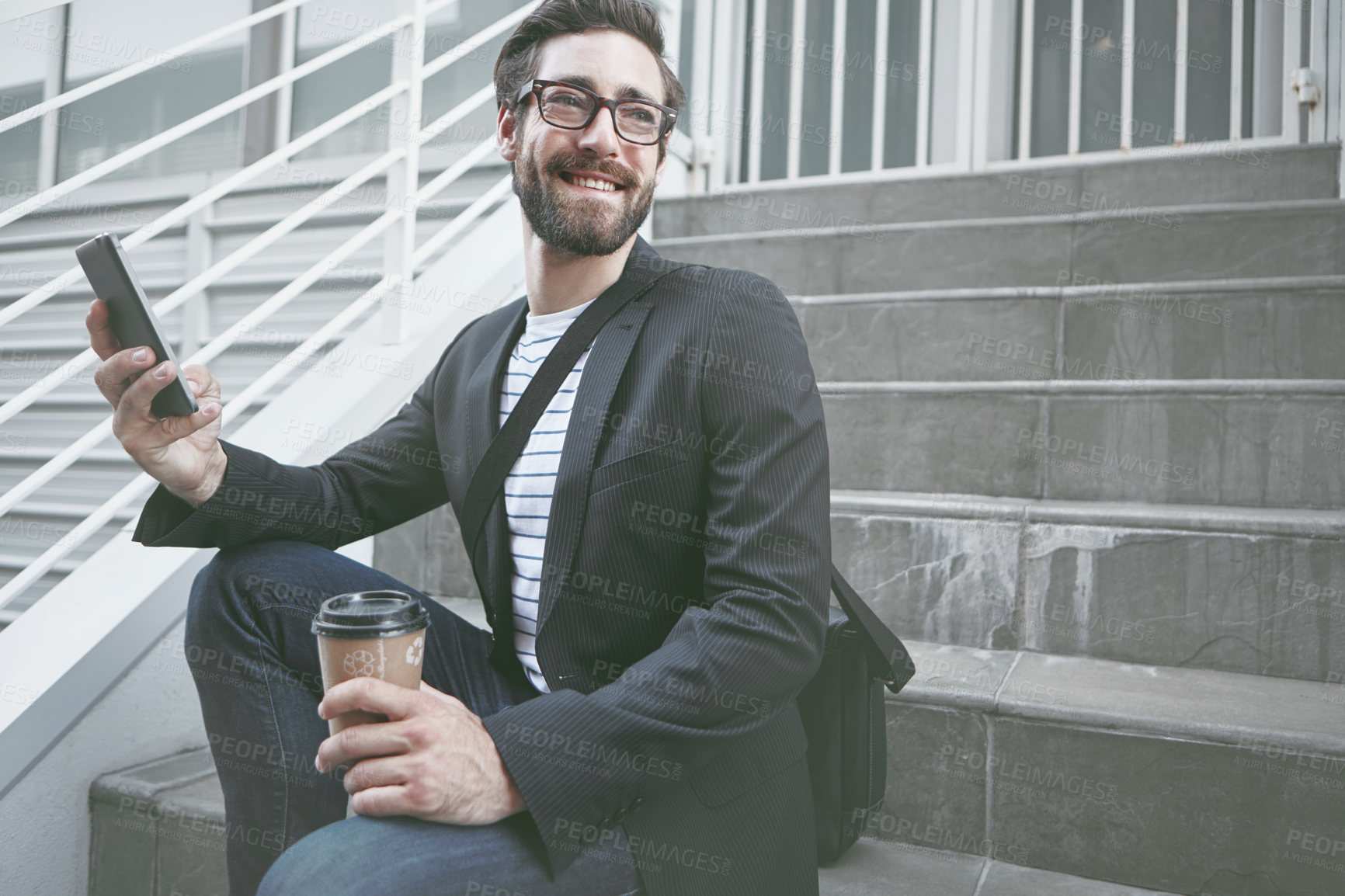 Buy stock photo A stylish young man sitting with his cellphone and a takeaway coffee in the city