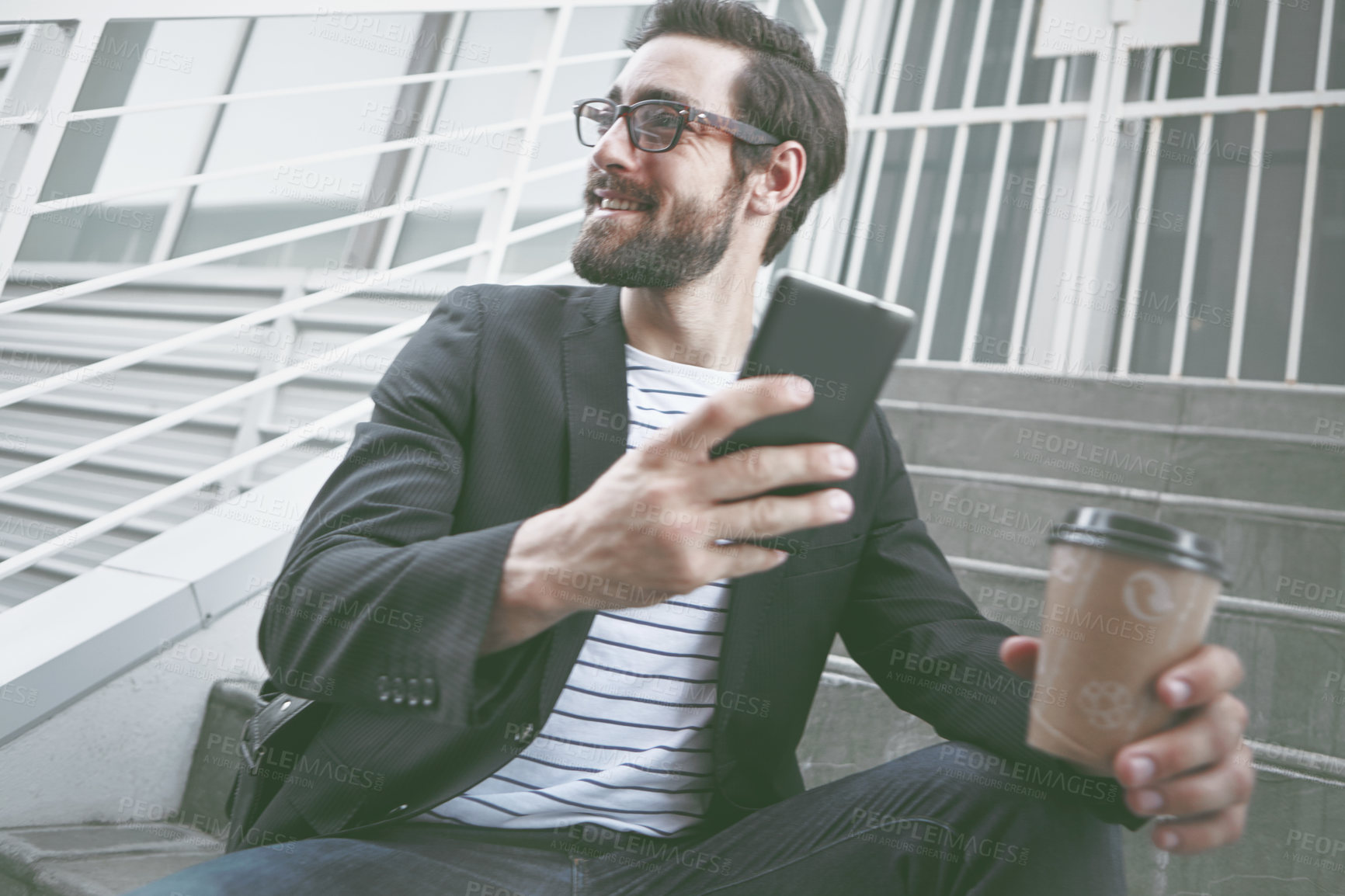 Buy stock photo A stylish young man sitting with his cellphone and a takeaway coffee in the city