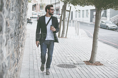 Buy stock photo Shot of a young man having a coffee on the go in the city