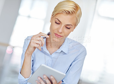 Buy stock photo Cropped shot of a young businsswoman using a digital tablet at her desk in the office