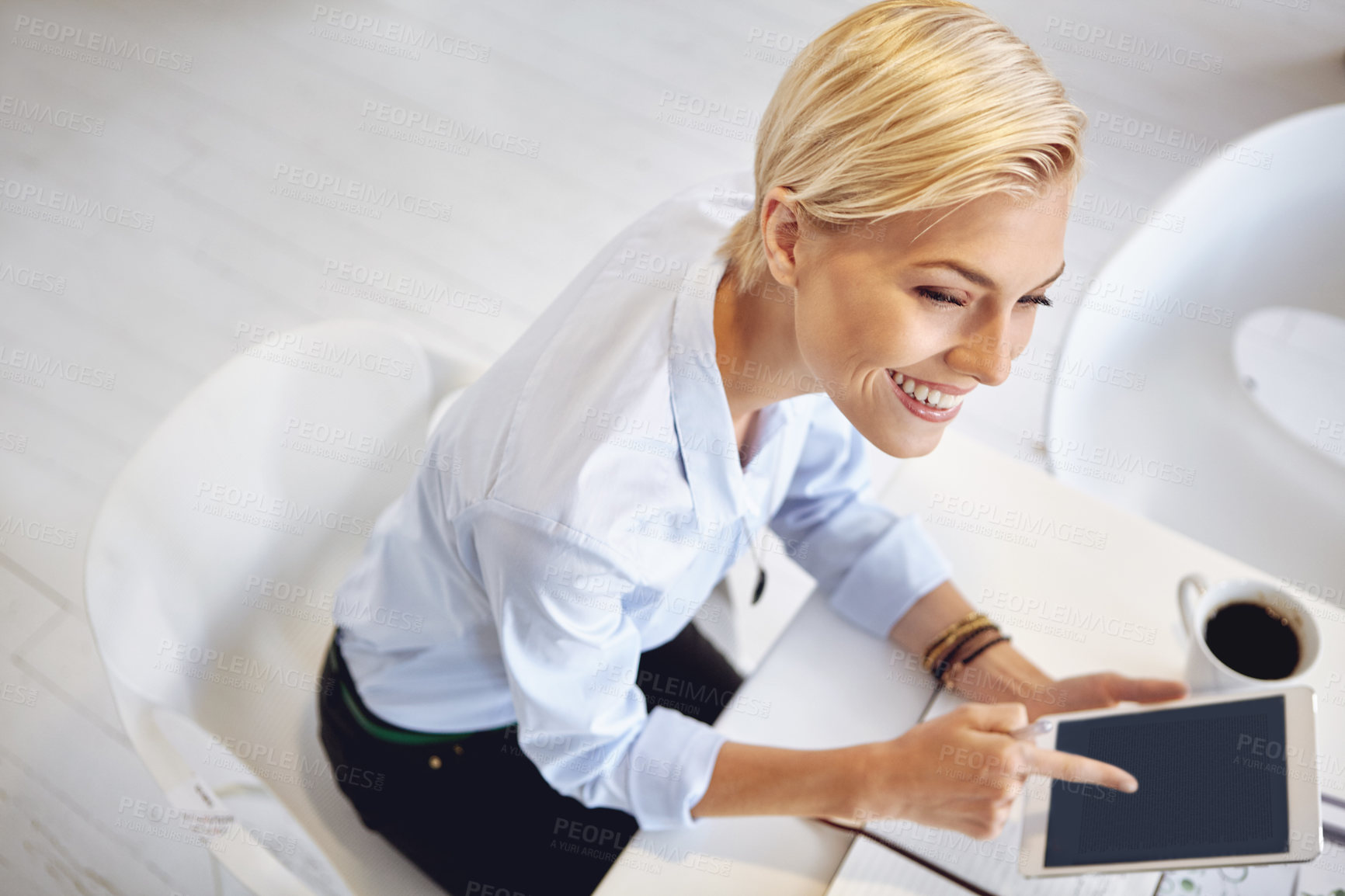 Buy stock photo High angle shot of a young businsswoman using a digital tablet at her desk in the office