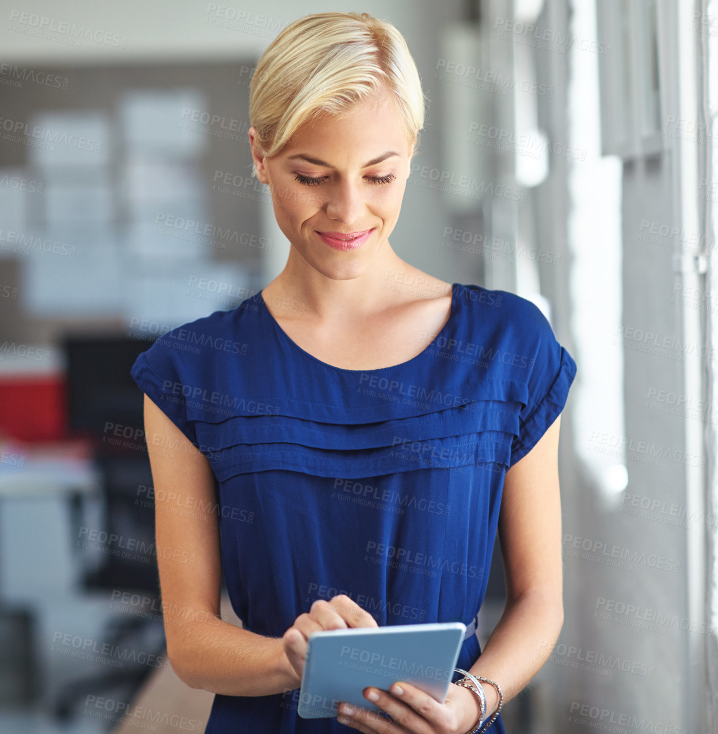 Buy stock photo Cropped shot of a young businesswoman working on her tablet in the office