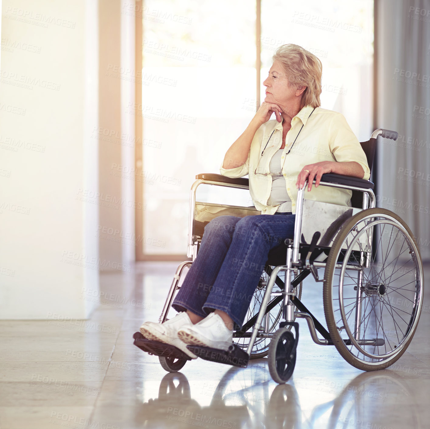 Buy stock photo Shot of a senior woman looking thoughtful while sitting in a wheelchair at home