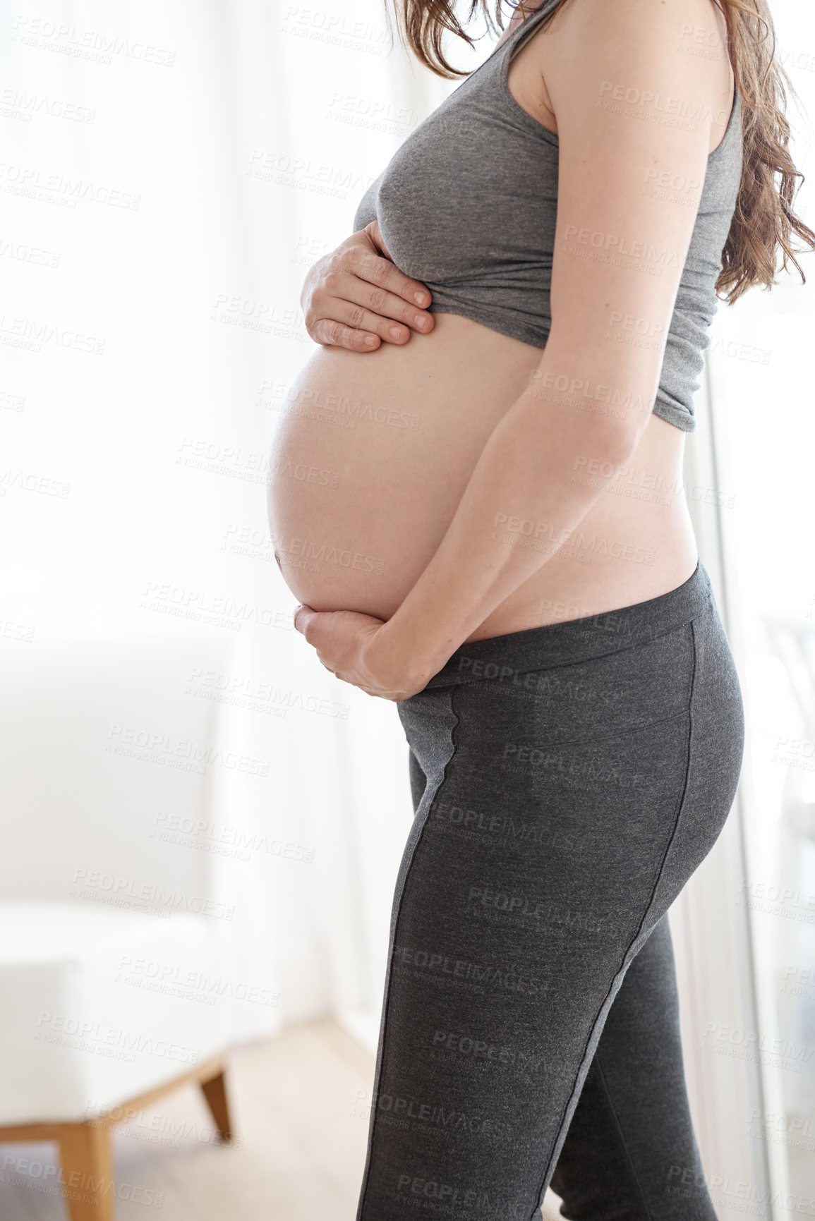 Buy stock photo Cropped shot of a pregnant woman standing in her home