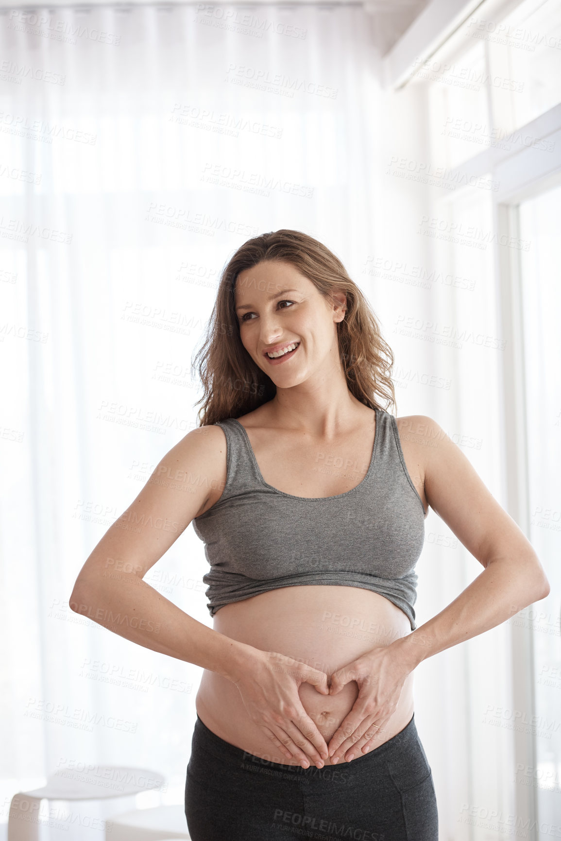 Buy stock photo Cropped shot of a young pregnant woman standing in her home
