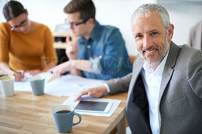 Buy stock photo Portrait of a mature businessman with his colleagues working in the background