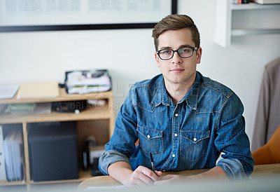 Buy stock photo Portrait of a confident young male designer sitting at her desk in an office
