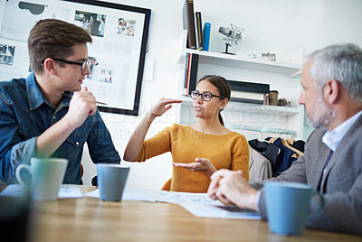 Buy stock photo Shot of a young businesswoman explaining something to her colleagues in a meeting