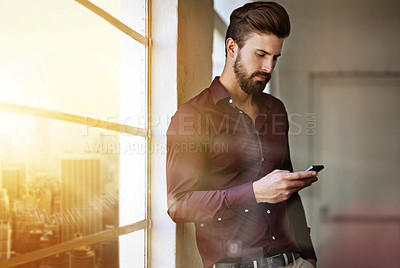 Buy stock photo Cropped shot of a businessman sending a text in his office