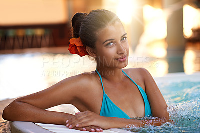 Buy stock photo Portrait of a young woman relaxing in a jacuzzi with a flower in her hair