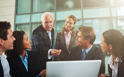 Buy stock photo Cropped shot of a group of businesspeople gathered around a laptop in the office