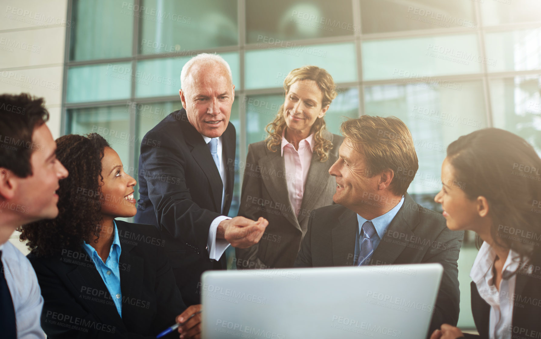 Buy stock photo Cropped shot of a group of businesspeople gathered around a laptop in the office