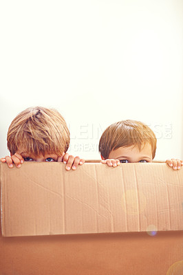 Buy stock photo Box, kids and eyes of siblings playing in a house with fun, bonding and hide and seek games. Cardboard, learning and curious boy children in a living room with fantasy, imagine or hiding at home
