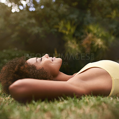 Buy stock photo Shot of a relaxed young woman lying on the grass with her eyes closed