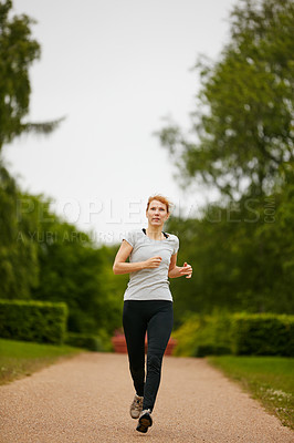 Buy stock photo Shot of a woman jogging down a foothpath in a park